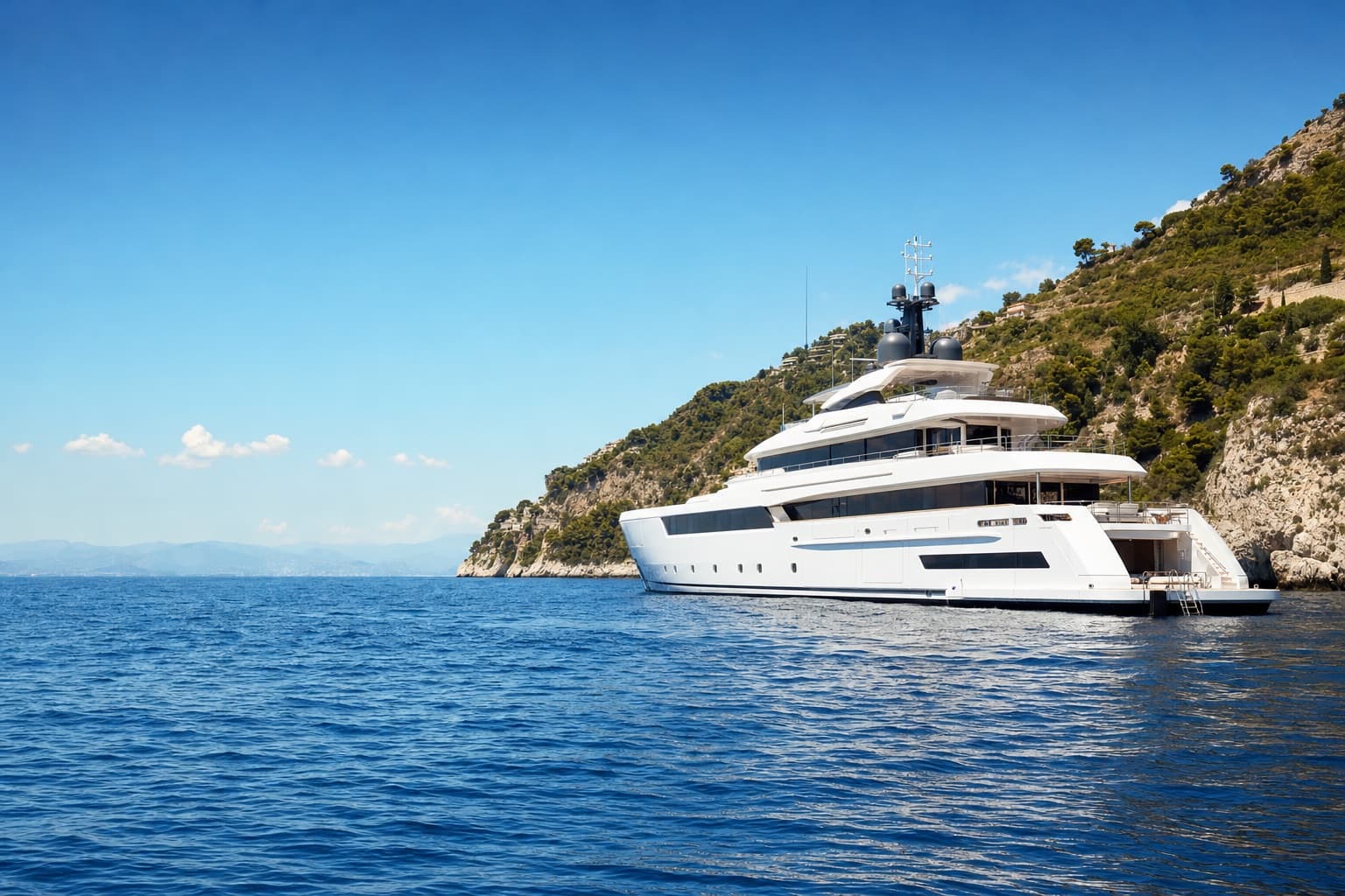 A white superyacht at anchor on open blue water